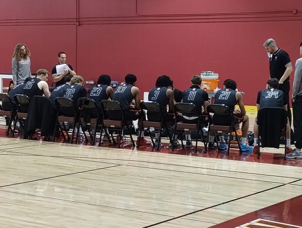 Skyline men's basketball team listens to head coach Justin Piergrossi speak at halftime.