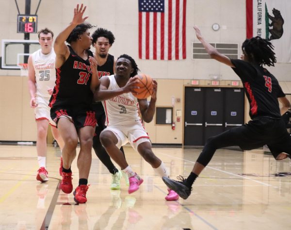 Skyline point guard Achilles Woodson pushes through defenders to attempt a layup.